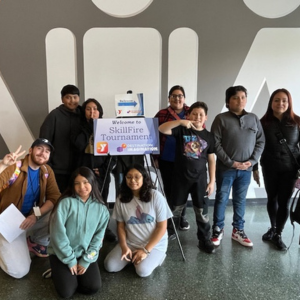 A group of students from Chicago, Illinois, who participated in DI's SkillFire program, pose for a photo together in front of the SkillFire Tournament sign. 