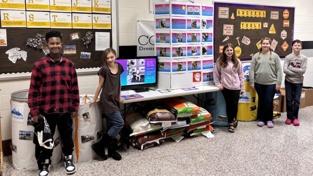 Students on the Pawfessionals Destination Imagination team stand near several pounds of dog food they have collected for the shelter.