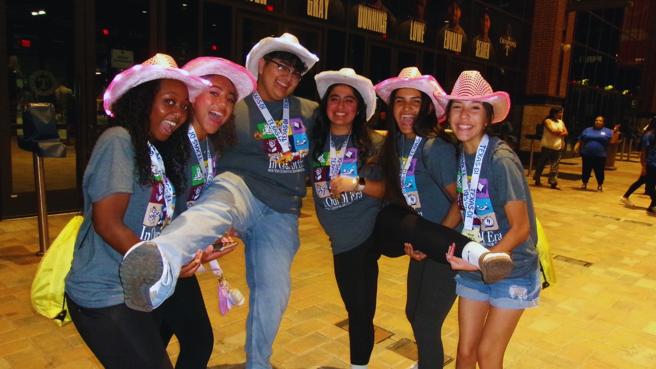 A Destination Imagination team from Texas poses for a celebratory photo wearing matching t-shirts and cowboy hats.